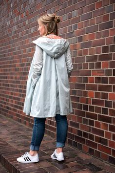 a woman standing in front of a brick wall with her back turned to the camera