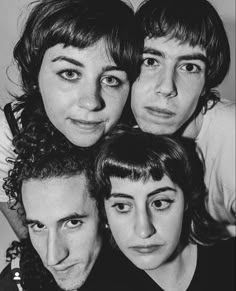 black and white photograph of four people posing for the camera with one woman's head tilted to the side