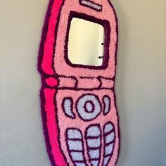 a pink cell phone hooked up to a wall with a mirror on it's side