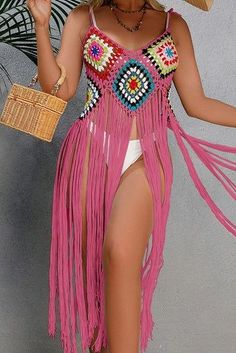 a woman in a pink dress and straw hat holding an umbrella while standing next to a wall