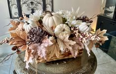 a basket filled with lots of white pumpkins and flowers on top of a table