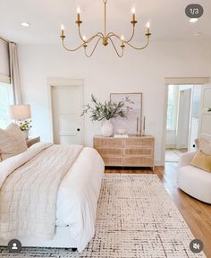 a large white bed sitting in a bedroom under a chandelier