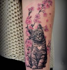 a cat with a heart on its paw is sitting in front of a cherry blossom branch