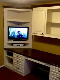 a flat screen tv sitting on top of a wooden desk next to a white cabinet