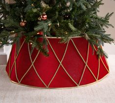 a christmas tree in a red velvet pot with gold trimmings and ornaments on top