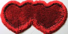 two red hearts shaped rugs sitting on top of a white floor next to each other