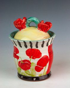 a red and white vase with flowers painted on it