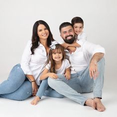 a family sitting on top of a bed posing for a photo with their baby boy