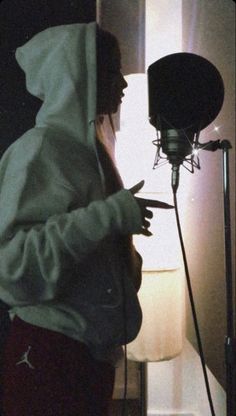 a person wearing a hoodie standing in front of a microphone