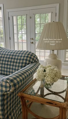 a blue and white checkered couch sitting in a living room next to a table with flowers on it