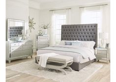 a bedroom with a bed, dressers and mirror in it's center area