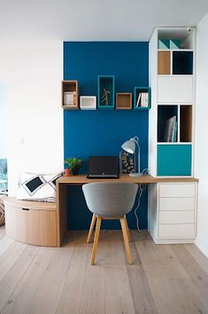 a desk with a laptop on top of it in front of a book shelf filled with books