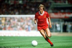 a soccer player is running with the ball in front of him and people watching from the stands