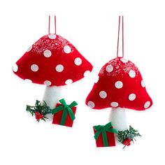 two red mushrooms with white dots and green bows are hanging from twine hooks on the wall