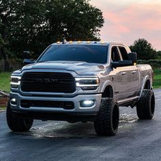 a silver ram truck parked on the side of a road with trees in the background