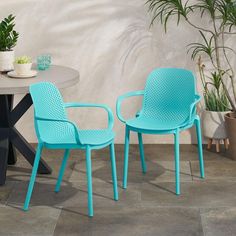 two chairs sitting next to each other near a table and potted plant on the floor