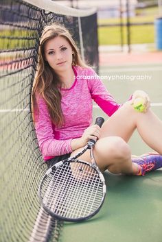 a woman sitting on the ground with a tennis racket and ball in her hand