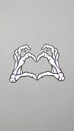 two hands making a heart shape with their fingers in the air on top of a gray wall