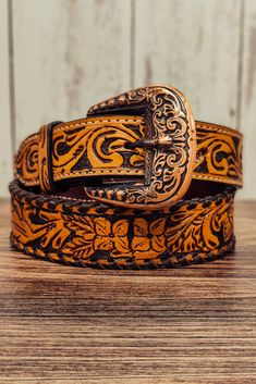 a brown and black leather belt sitting on top of a wooden table