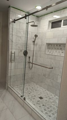 a walk in shower sitting next to a white tiled wall and floor with glass doors