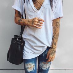 a woman with tattoos on her arm holding a black purse