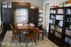 a dining room table with chairs and bookshelves in the background on carpeted floor