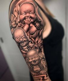 a woman with a black and grey tattoo on her arm is holding a baby buddha