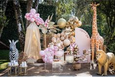 an outdoor party setup with balloons, giraffes and other items on the table