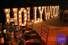 the hollywood sign is lit up at night with lights on it and place settings for dinner