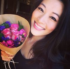 a woman holding a bouquet of flowers in front of her face and smiling at the camera