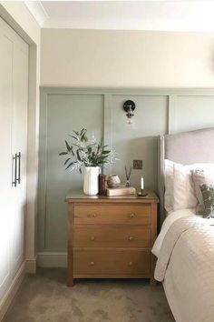 a white bed sitting next to a wooden dresser with flowers on it's top