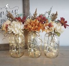 three mason jars filled with flowers and fairy lights