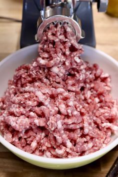 ground beef being processed in a bowl with a meat grinder on the counter top