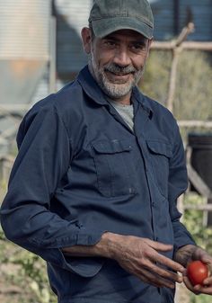 an older man holding a tomato in his hands