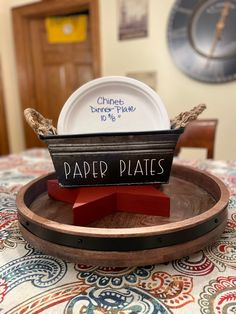 a paper plate is sitting on top of a wooden tray with a sign that says paper plates