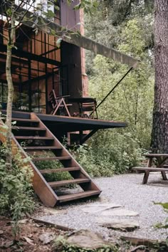 an outdoor area with steps leading up to a house in the woods, and a picnic table next to it