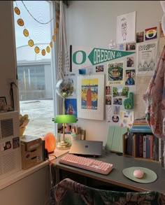 a desk with a laptop computer sitting on it's side next to a window