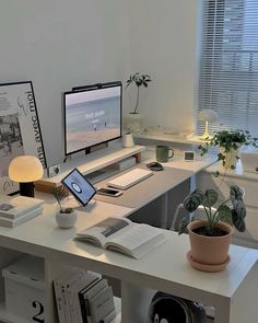 a desk with a computer monitor, laptop and books on it