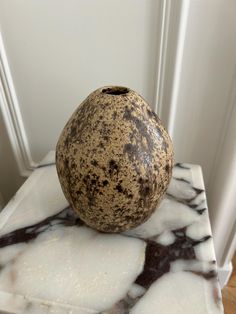 a brown and white vase sitting on top of a marble table next to a door