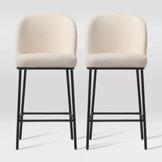 two white upholstered stools with black legs, one on the left and one on the right