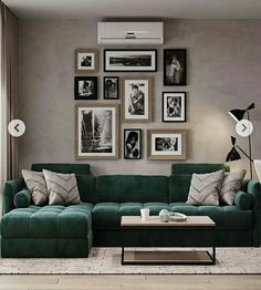 a living room with green couches and pictures on the wall above them, along with a coffee table