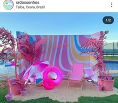 there is a pink tent with chairs and palm trees in front of the pool area