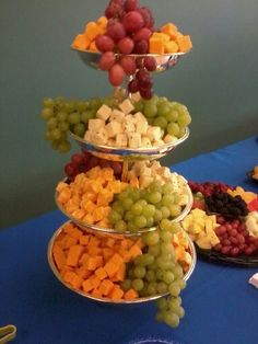 three tiered trays filled with grapes, cheese and crackers on a table