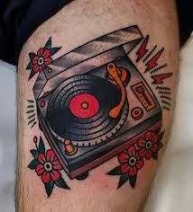 a man's thigh with an old school record player and flowers on the side