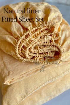 a pile of yellow sheets with the words natural linen fitted sheet set on top of it