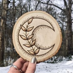 a person holding up a wooden plate with an image of a crescent and leaves on it