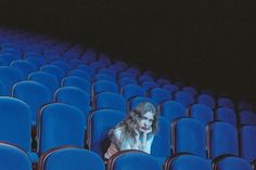 a woman sitting in the middle of an empty theater