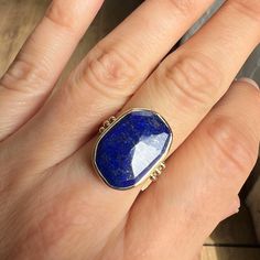 We love this cocktail Lapis ring set in 14k yellow gold. It is accented with gold beads and sits beautifully on Emily's signature Sterling Silver band. Approximate stone size is 20mm x 14mm. Approx ct weight: 10.6 ct Mohs hardness: 5-6 This mixed metal piece is handmade to order in Emily's Hudson Valley studio. Please allow for slight variations in stone color, size and shape. Please allow 14-21 days to ship unless the piece is in stock. If you have questions about sizing, shipping or custom ord Yellow Gold 14k Rings With Natural Stones, Elegant Yellow Gold Ring With Natural Stones, Elegant Yellow Gold Rings With Natural Stones, Gold Gemstones Ring With Gemstone Accents, Unique 14k Gold Gemstone Jewelry, 14k Gold Fine Jewelry With Large Stone, Sterling Silver Gold Rings With Gemstone, Adjustable Gold Ring With Gemstone Accents, 14k Gold Ring With Gemstone Accents