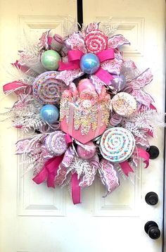 a wreath with candy and lollipops hanging on the front door to decorate it