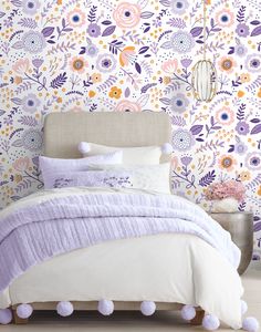 a bed with purple pom poms on it and a floral wallpaper in the background